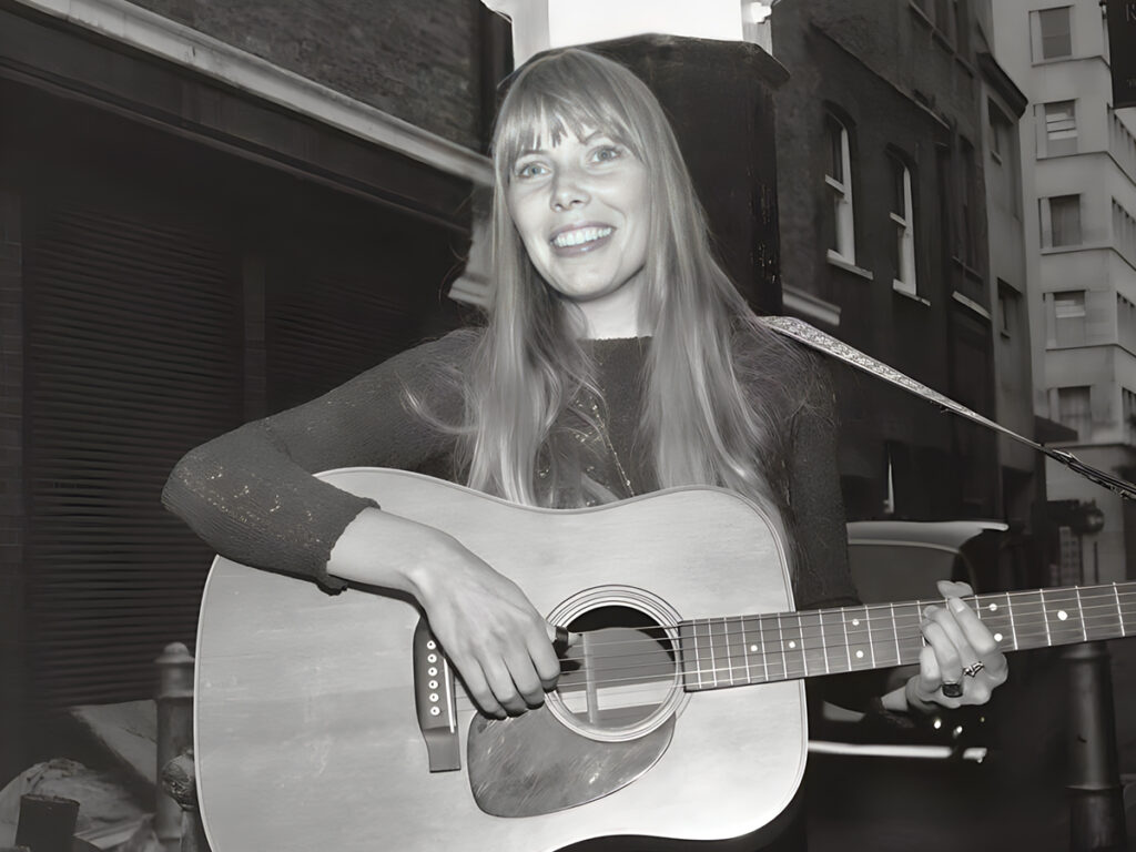 Joni Mitchell plays guitar outside The Revolution Club in London, 1968