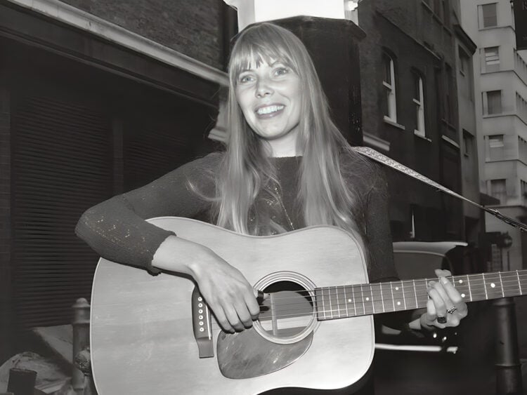 Joni Mitchell plays guitar outside The Revolution Club in London, 1968