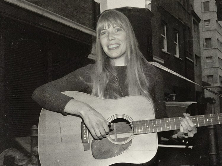 Joni Mitchell plays guitar outside The Revolution Club in London, 1968