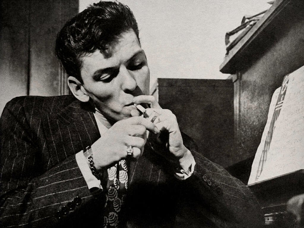 Frank Sinatra smoking by a piano in 1946.